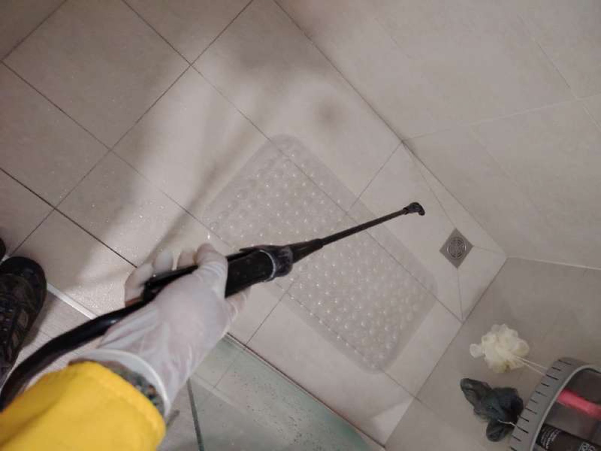 Pest control spraying on a bathroom floor next to the drain