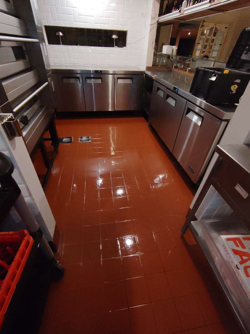 Clean commercial kitchen with gleaming floor and refrigeration units after EcoPlagas service