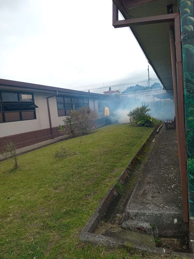 Técnico de EcoPlagas aplicando tratamiento en el exterior de una escuela