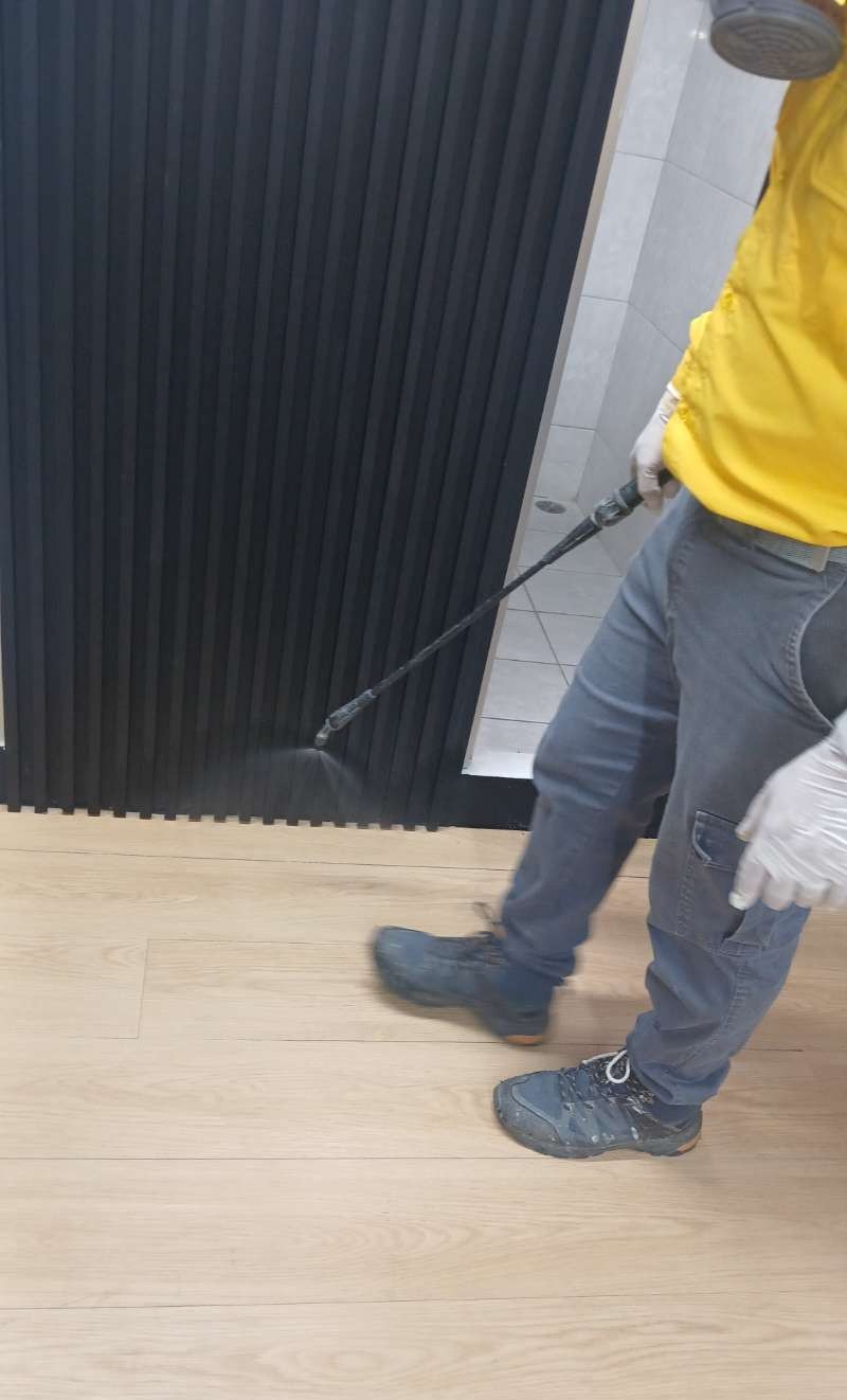 Technicien appliquant une pulvérisation à la lance sur un plancher en bois