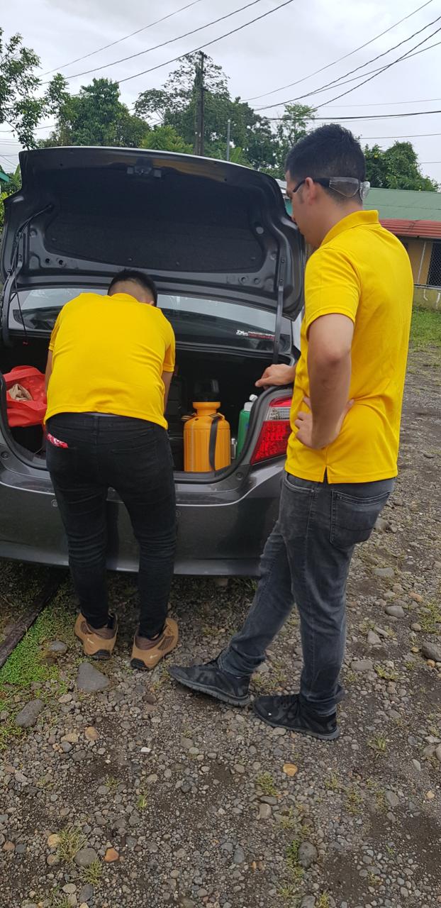 Cargando el equipo de fumigación en el baúl de un carro familiar